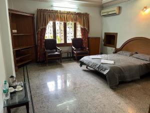 a bedroom with a bed and two chairs and a table at Stone rock castle in Hyderabad