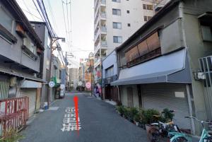 an empty street in an asian city with buildings at 静響の宿 Silent Echo Inn in Osaka