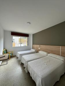 a bedroom with three beds and a window at Hotel Angelito in O Grove