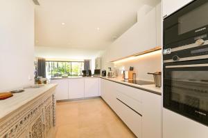 una cocina con armarios blancos y horno negro en La Valvega 47, en Mijas Costa