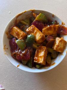 a bowl of food with tofu and vegetables at Hotel Ambassador Inn in Gwalior