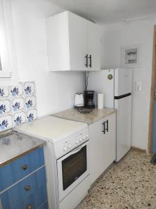 a kitchen with white appliances and blue and white cabinets at Θέα από ψηλά in Áyioi Apóstoloi