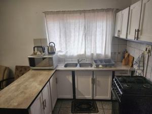 a small kitchen with a sink and a microwave at Cassiandra Place unit 1 in Richards Bay