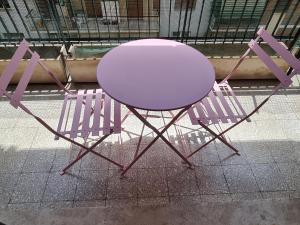 Una mesa rosa y dos sillas moradas en una acera en Danielle B&B, en Roma