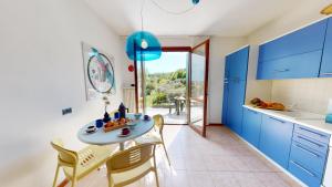 kuchnia z niebieskimi szafkami i stołem z krzesłami w obiekcie Domus Minervae - BGL w Manerba del Garda