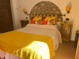 sypialnia z łóżkiem z żółtym kocem w obiekcie Agriturismo La Castellina w mieście Saturnia