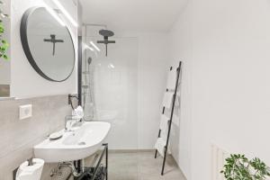 un bagno bianco con lavandino e specchio di Black Forest Design Apartment a Bad Wildbad Altre 27 foto