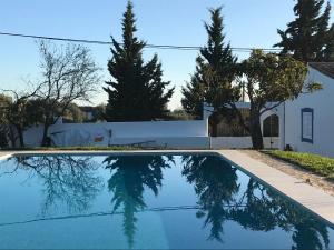 a swimming pool in front of a white house with trees at Monte das Estrelas in Tavira
