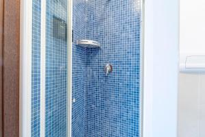 a shower with a glass door with a blue tile wall at Certosa House - Milano in Milan +20 photos