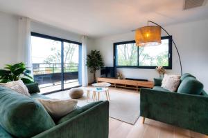 a living room with two green couches and a table at Villa Sunset 2 prestigious Balinese swimming pool sea view for 8 people in Lacanau-Océan