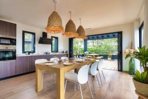 a dining room and kitchen with a table and chairs at Villa Sunset 2 prestigious Balinese swimming pool sea view for 8 people in Lacanau-Océan +25 photos
