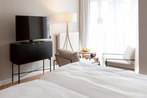a bedroom with a bed and a flat screen tv at Vju Hotel Rügen in Göhren