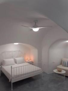 Un dormitorio blanco con una cama y un ventilador de techo. en Unique small stonehouse at Thira, en Megalokori 26 fotos más