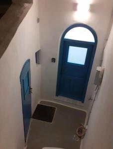 a bathroom with a blue door and a window at Unique small stonehouse at Thira in Megalochori