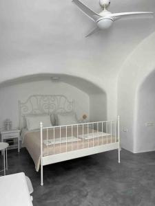 ein Schlafzimmer mit einem weißen Bett mit Deckenventilator in der Unterkunft Unique small stonehouse at Thira in Megalochori + 25 Fotos