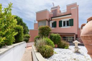 a pink house with green shutters and plants at Villa Chioma by Mmega in Chioma