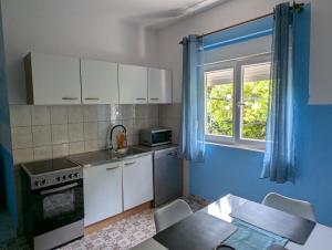 a kitchen with white cabinets and a table and a window at Apartments Lilly Weiss in Banjol