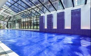 a large swimming pool in a building with a glass ceiling at CBD Apartment, Sleeps 4 with Free Car Park in Melbourne
