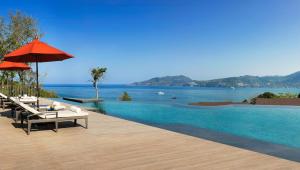 a swimming pool with a table and an umbrella at Amari Phuket in Patong Beach