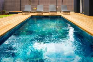 a swimming pool with blue water and chairs in it at Villa Sunset 2 prestigious Balinese swimming pool sea view for 8 people in Lacanau-Océan