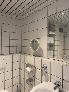 a white tiled bathroom with a sink and a mirror at Landhaus Alpinia in Berlin +66 photos