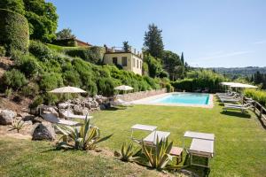 a yard with a pool and chairs and umbrellas at Agriturismo Bio Fattoria Bacio in Certaldo