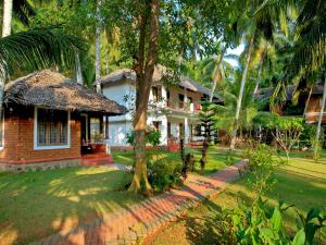 a house with a palm tree in front of it at Abad Harmonia Ayurvedic Beach Resort in Kovalam