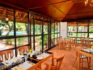 a dining room with tables and chairs and windows at Abad Harmonia Ayurvedic Beach Resort in Kovalam