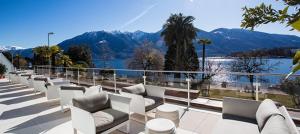 a row of white couches on a balcony overlooking a lake at Hotel la Palma au Lac in Locarno