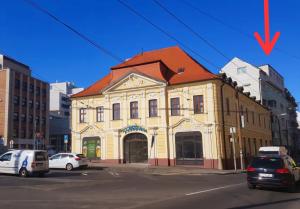 a yellow building with a red roof on a street at Old town cozy Studio in City Center in Bratislava