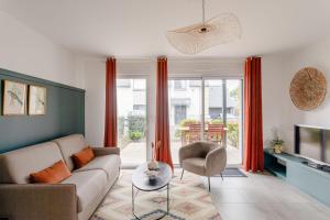 a living room with a couch and a tv at Les Sternes - Appt proche de la plage in Saint Malo