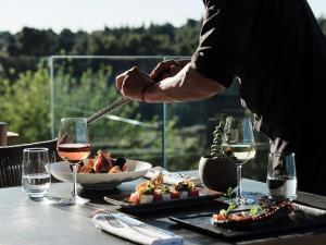 a person serving food on a table with glasses of wine at Cora Hotel & Spa in Afitos