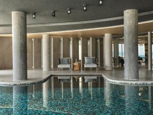 a swimming pool in a building with columns at Cora Hotel & Spa in Afitos