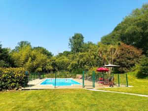 a swimming pool with a table and an umbrella at Gîte du Nouveau Monde in Langoëlan