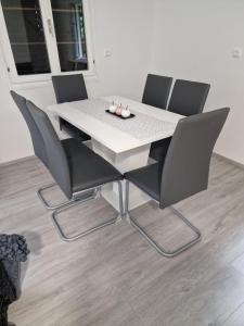 a white table with four chairs and a white table at Hiška 111 s kopalnimi kartami in Brežice