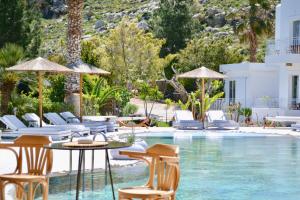 a swimming pool with chairs and a table and a pool at Caesars Gardens Hotel & Spa - Adults Only in L&iacute;ndos