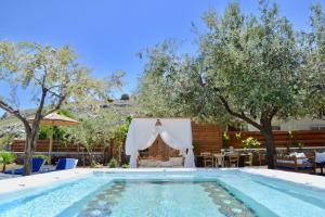 a swimming pool with a table and chairs and trees at Caesars Gardens Hotel & Spa - Adults Only in L&iacute;ndos