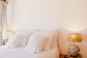 a white bed with white pillows and a lamp at Caesars Gardens Hotel & Spa - Adults Only in L&iacute;ndos