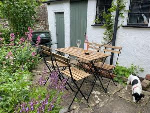 a dog standing next to a wooden table and chairs at Fettlers Cottage, Cumbria in Kirkby Stephen