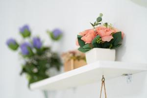 a white vase with pink flowers on a shelf at Yang yang Sanjang Love Story in Yangyang
