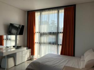 a bedroom with a bed and a tv and a window at Jeju Jayle Blanc in Jeju