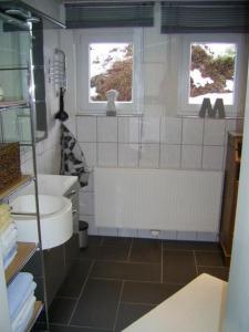 a bathroom with a tub and a toilet and two windows at Ferienwohnung Veronika Pape in Schmallenberg