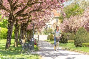 a woman riding a bike down a path in a park at APARTMENT KLAGENFURT Villa Frank No1 - with Free Parking, Air Conditioning, Smart-TV & Self Check-in in Klagenfurt