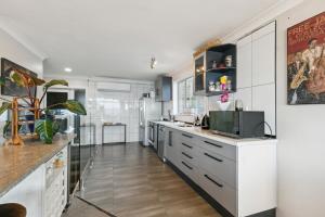 cocina con armarios blancos y encimera en Pacific Ocean seafront home near airport, en Wellington