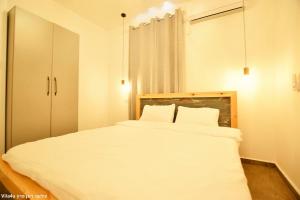a bedroom with a large white bed with two pillows at אחוזת מיקונוס - וילה יוונית מושלמת עם בריכה מחוממת ומקורה in Yarka
