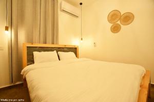 a bedroom with a large bed with white sheets at אחוזת מיקונוס - וילה יוונית מושלמת עם בריכה מחוממת ומקורה in Yarka