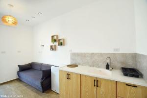 a kitchen with a sink and a couch in a room at אחוזת מיקונוס - וילה יוונית מושלמת עם בריכה מחוממת ומקורה in Yarka +19 photos