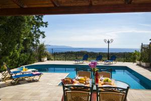 a patio with a table and chairs next to a swimming pool at Thalia Villas in Trapezaki