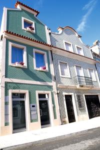 ein grünes Gebäude mit Blumen in den Fenstern in der Unterkunft Casa do Cais in Aveiro