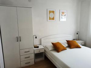 a bedroom with a white bed with two orange pillows at Apartments Villa Vanja in Povlja